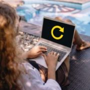 Woman refocusing on her business while working on a laptop by the pool