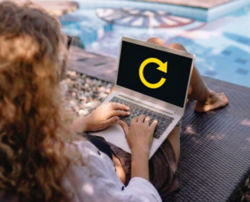 Woman refocusing on her business while working on a laptop by the pool